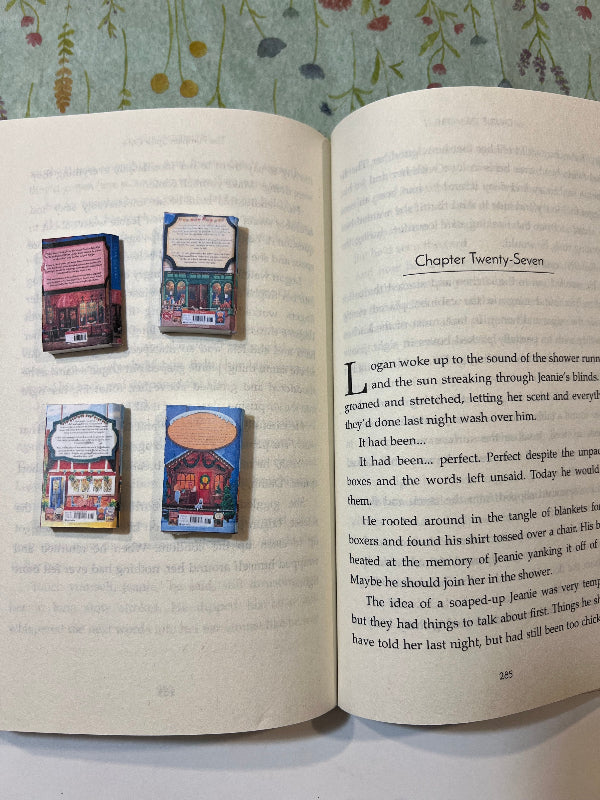 Four small books or notebooks placed on an open book with text.