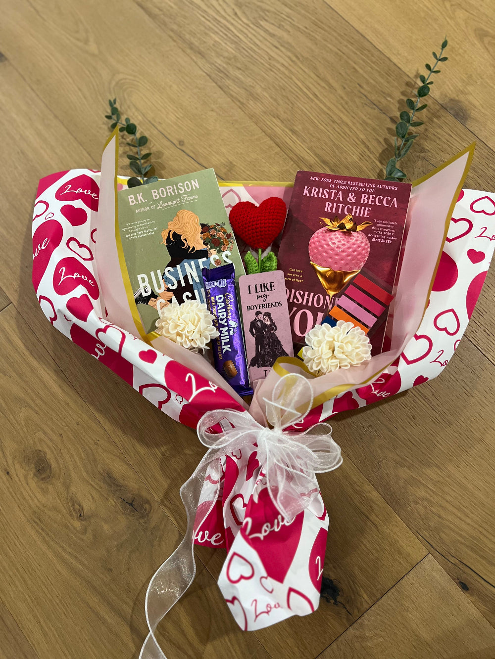 Bouquet of books and small items wrapped in a decorative paper with heart patterns