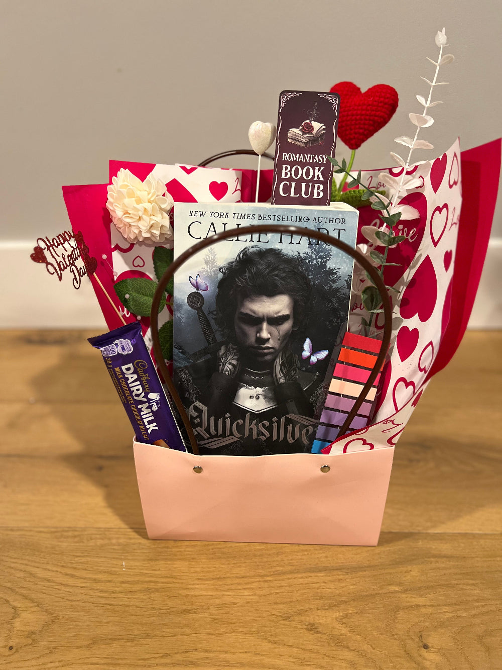 Gift basket with book, chocolate, and decorative elements on a wooden surface