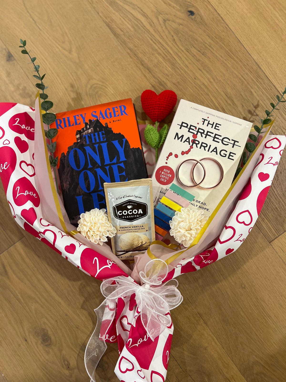 Book bouquet with 'The Only One' and 'The Perfect Marriage' books, a box of cocoa, and decorative elements